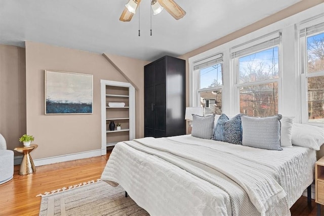 bedroom featuring ceiling fan, wood-type flooring, and multiple windows