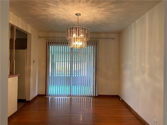 unfurnished dining area with hardwood / wood-style flooring and a chandelier