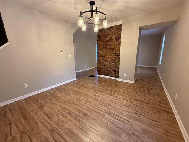 unfurnished dining area with an inviting chandelier and hardwood / wood-style flooring