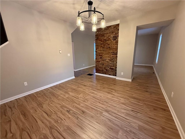 unfurnished dining area featuring wood-type flooring and a chandelier