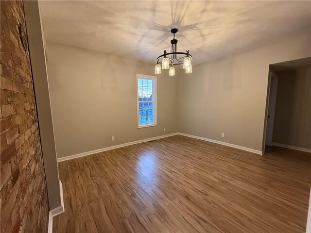 spare room featuring hardwood / wood-style flooring and a notable chandelier