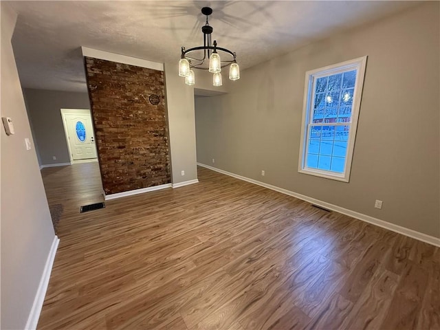 unfurnished room with wood-type flooring and a chandelier