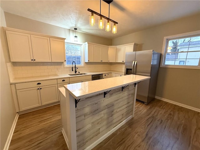 kitchen featuring sink, white cabinetry, stainless steel appliances, a kitchen island, and decorative light fixtures