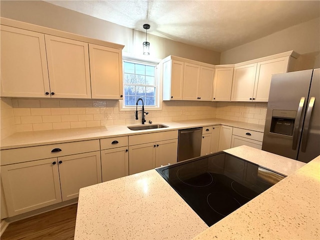 kitchen with appliances with stainless steel finishes, decorative light fixtures, sink, and backsplash