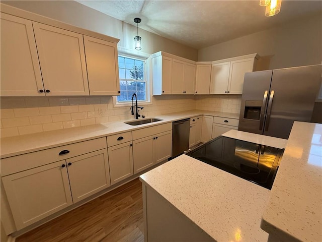 kitchen featuring sink, decorative light fixtures, backsplash, appliances with stainless steel finishes, and white cabinets