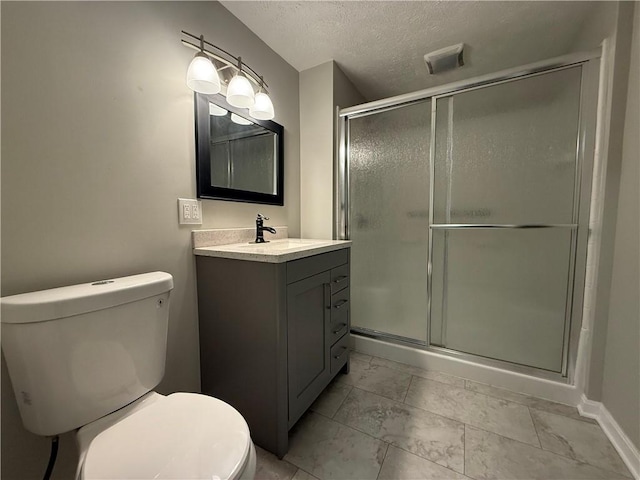 bathroom featuring vanity, a textured ceiling, a shower with shower door, and toilet