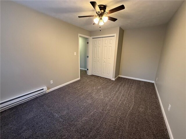 unfurnished bedroom with ceiling fan, a baseboard heating unit, dark carpet, and a closet