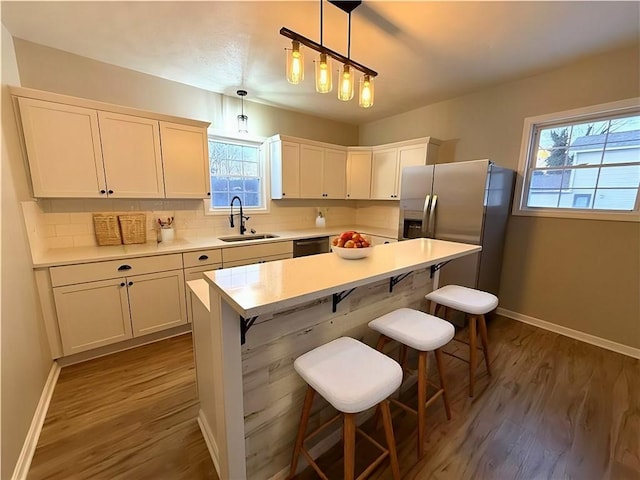 kitchen with sink, white cabinetry, hanging light fixtures, appliances with stainless steel finishes, and a kitchen island