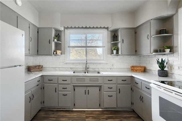 kitchen featuring gray cabinets, tasteful backsplash, sink, dark hardwood / wood-style flooring, and white appliances