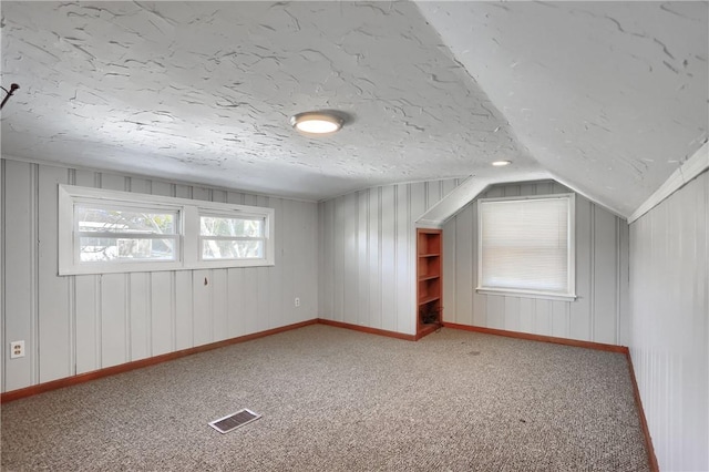 bonus room featuring lofted ceiling, carpet floors, and a textured ceiling