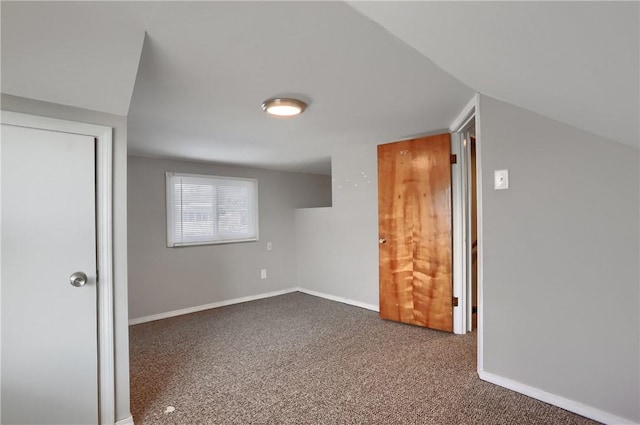 bonus room with vaulted ceiling and dark colored carpet