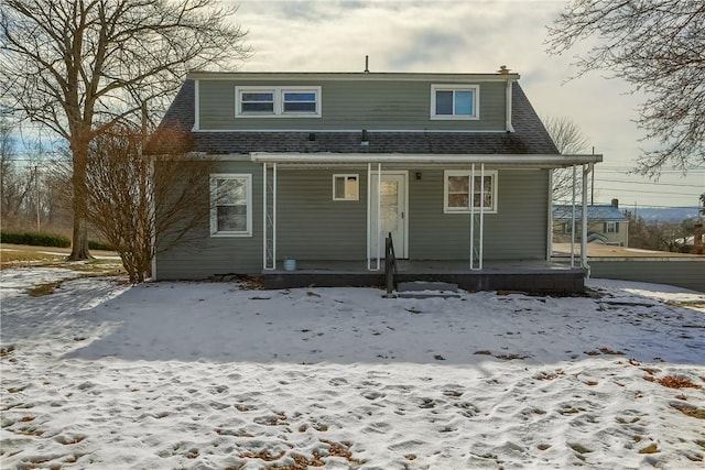 snow covered rear of property with covered porch