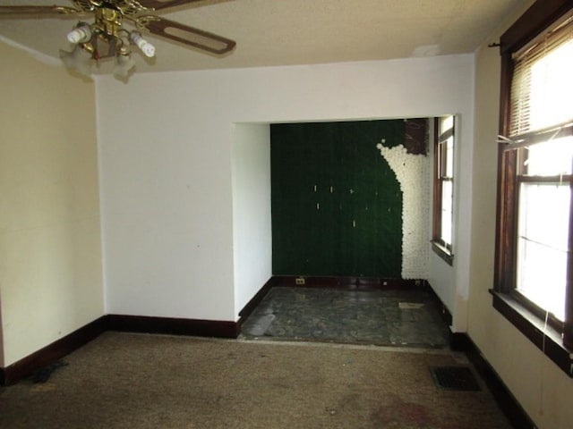 unfurnished room featuring a healthy amount of sunlight and dark colored carpet