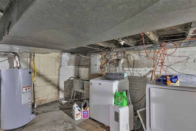 utility room with electric panel, washer and clothes dryer, and water heater