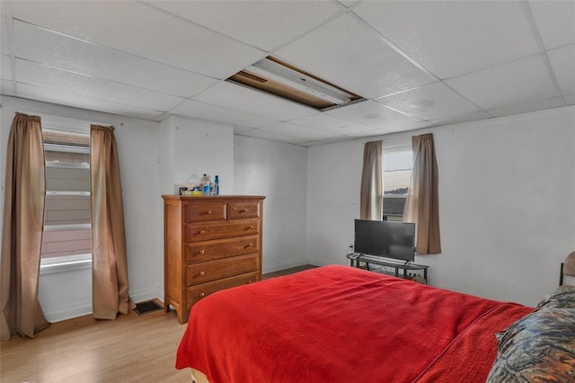 bedroom featuring a drop ceiling and light wood-type flooring