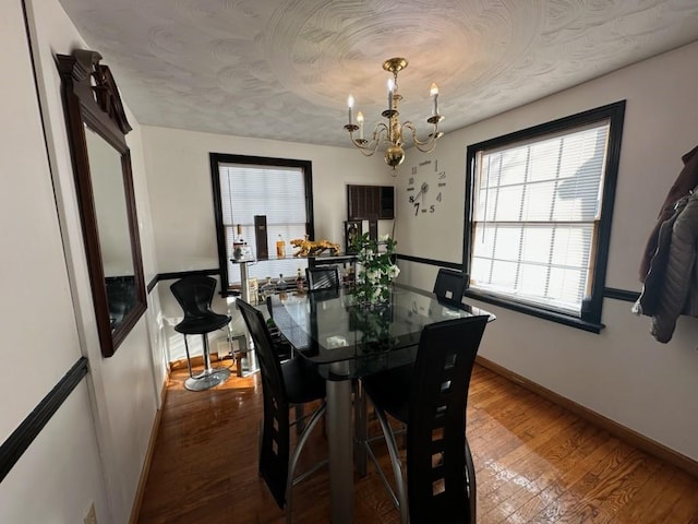 dining space with hardwood / wood-style floors, a notable chandelier, and a textured ceiling