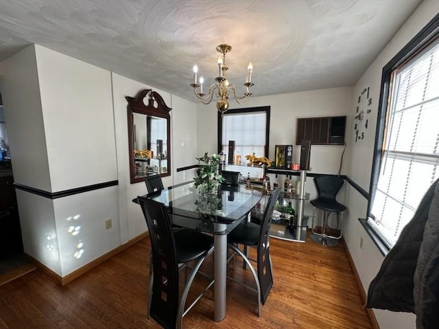 dining room with a textured ceiling, wood-type flooring, and a chandelier