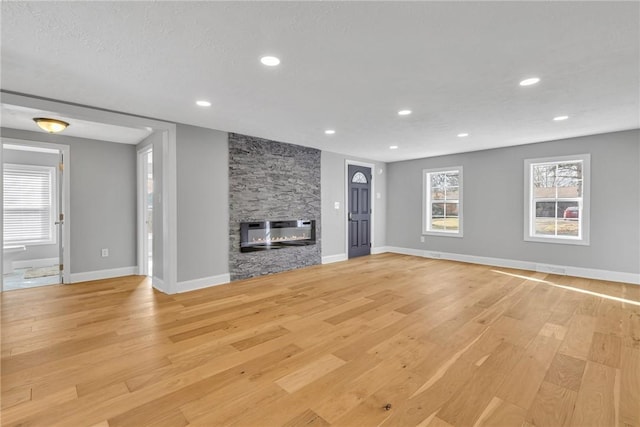 unfurnished living room with a stone fireplace and light hardwood / wood-style flooring