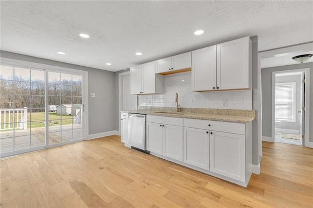 kitchen featuring white cabinetry, sink, stainless steel dishwasher, and light hardwood / wood-style floors