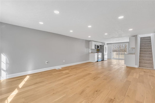 unfurnished living room featuring sink, a textured ceiling, and light hardwood / wood-style flooring