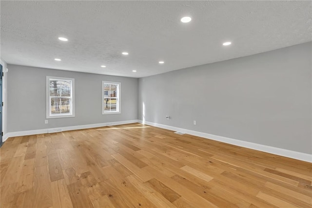 unfurnished room with light hardwood / wood-style floors and a textured ceiling