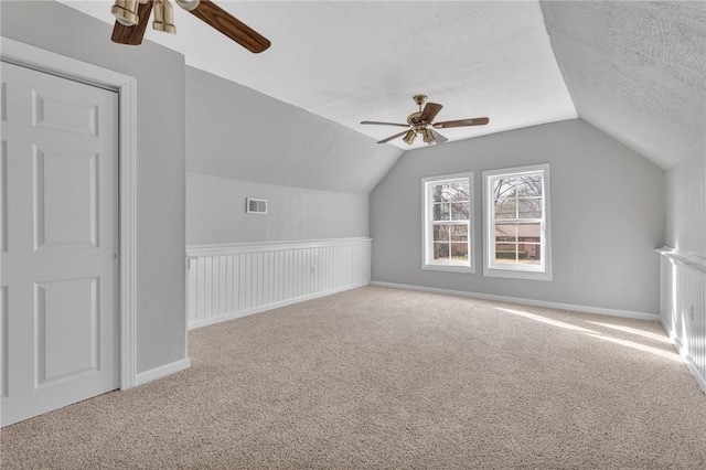 bonus room featuring ceiling fan, lofted ceiling, carpet flooring, and a textured ceiling