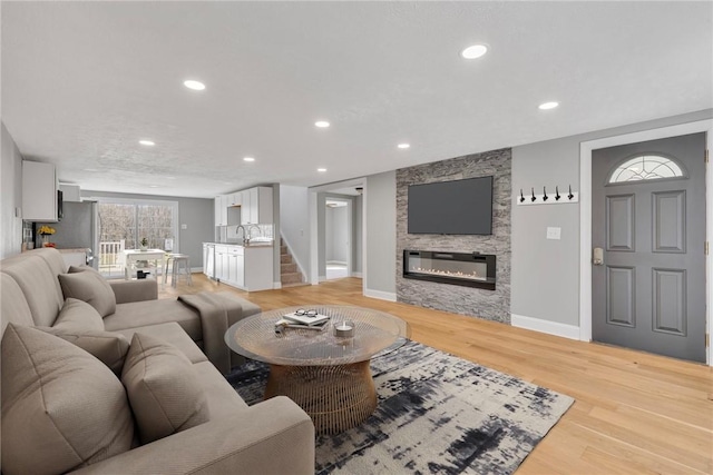 living room with sink, a fireplace, and light wood-type flooring