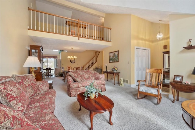 carpeted living room featuring a chandelier and a high ceiling