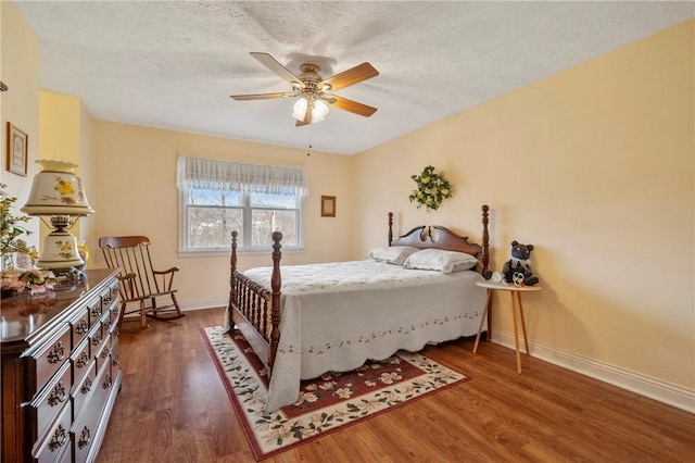 bedroom with dark wood-type flooring, ceiling fan, and a textured ceiling