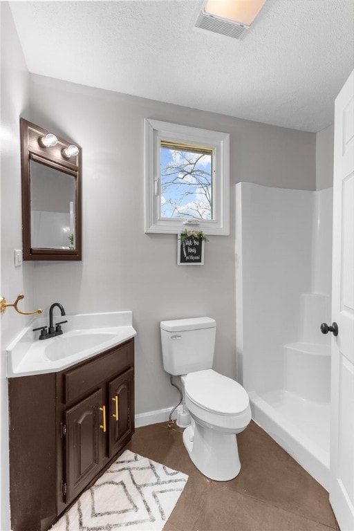 bathroom featuring vanity, walk in shower, a textured ceiling, and toilet