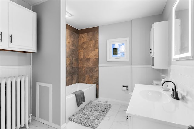 bathroom with vanity, radiator, and tiled shower / bath