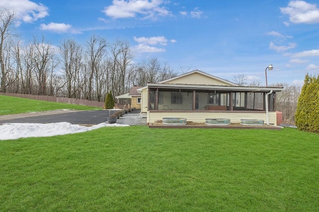 rear view of house featuring a yard and a sunroom