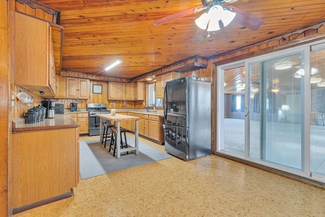 kitchen with stainless steel gas stove, wooden ceiling, black refrigerator, kitchen peninsula, and ceiling fan