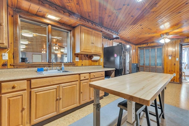 kitchen featuring black fridge, wooden ceiling, sink, and wood walls