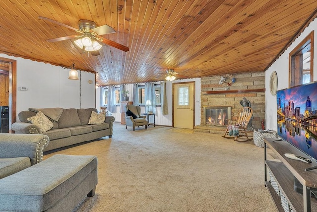 living room with wood ceiling, ceiling fan, a stone fireplace, and carpet