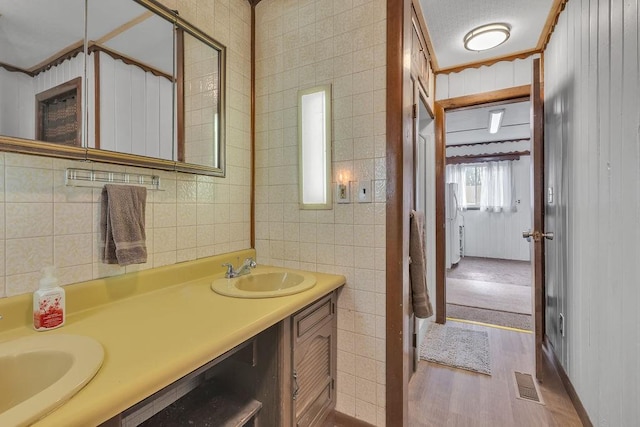 bathroom with hardwood / wood-style flooring, vanity, tasteful backsplash, and tile walls