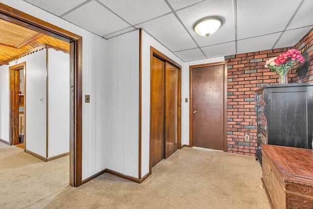 hall featuring a paneled ceiling and light colored carpet