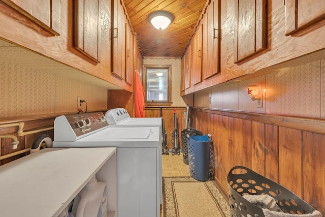 clothes washing area with sink, wood ceiling, washing machine and dryer, cabinets, and wood walls