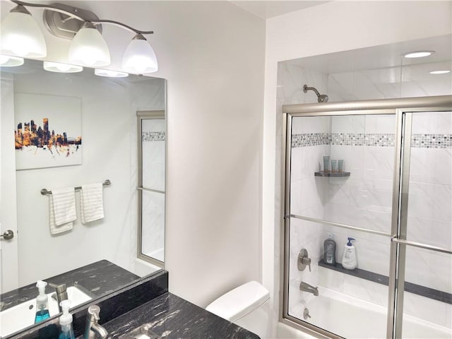 full bathroom featuring vanity, shower / bath combination with glass door, and toilet