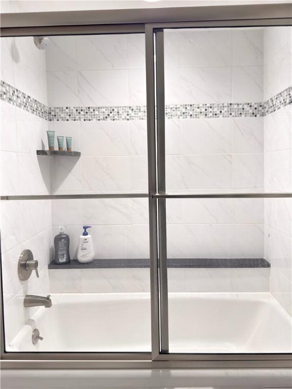 bathroom with bath / shower combo with glass door