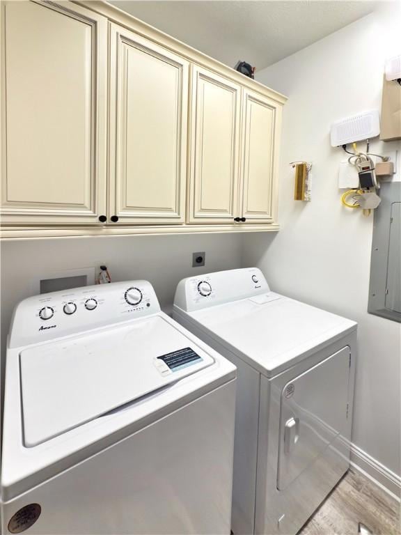 laundry room with independent washer and dryer, hardwood / wood-style flooring, electric panel, and cabinets