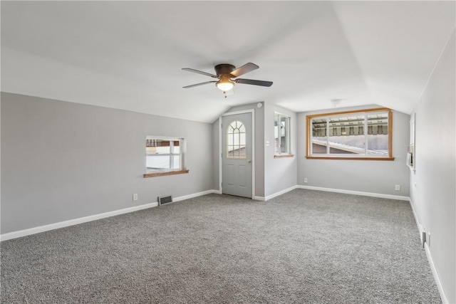 empty room with lofted ceiling, ceiling fan, and carpet