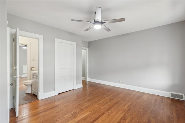 unfurnished bedroom featuring hardwood / wood-style floors, ceiling fan, and ensuite bathroom