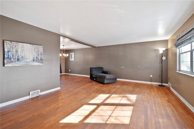 unfurnished room featuring wood-type flooring and an inviting chandelier