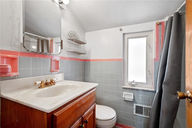 bathroom with vanity, vaulted ceiling, tile walls, and toilet