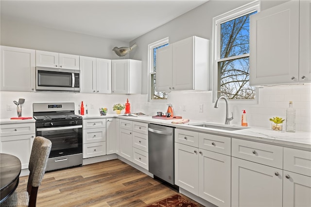 kitchen with white cabinetry, stainless steel appliances, sink, and wood-type flooring