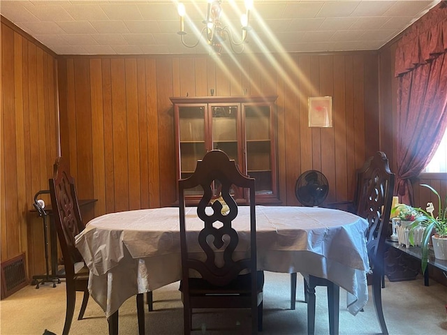 dining space featuring wooden walls and light colored carpet