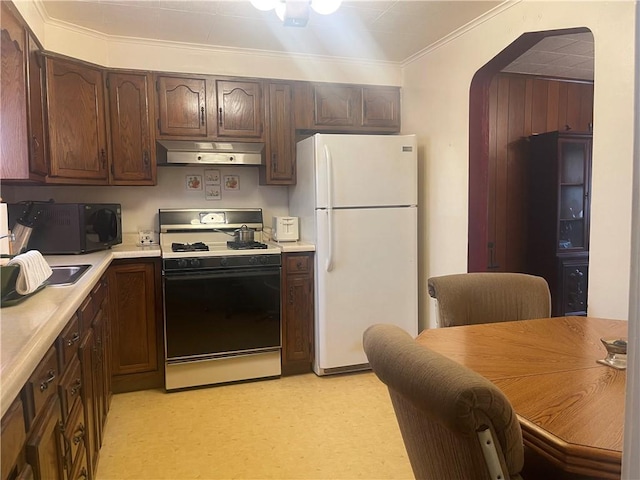 kitchen with crown molding, dark brown cabinets, gas range oven, and white fridge