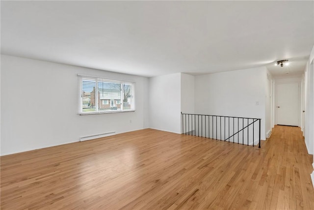 spare room featuring a baseboard heating unit and light wood-type flooring