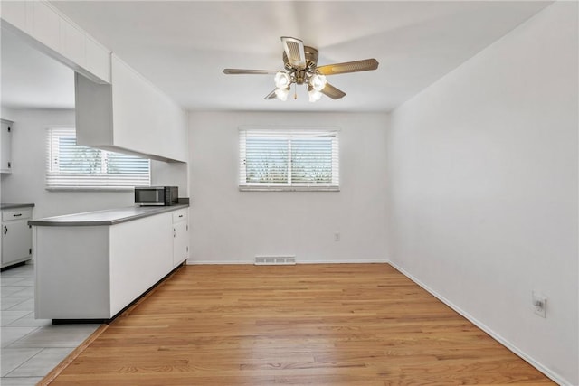 kitchen featuring white cabinets, ceiling fan, and light hardwood / wood-style flooring